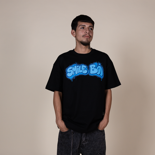A man wearing a black t-shirt with a blue 'SMILE BOY' graphic, standing against a plain beige background.