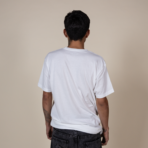 A man viewed from behind wearing a plain white short-sleeve t-shirt and dark gray jeans, standing against a solid beige studio background.