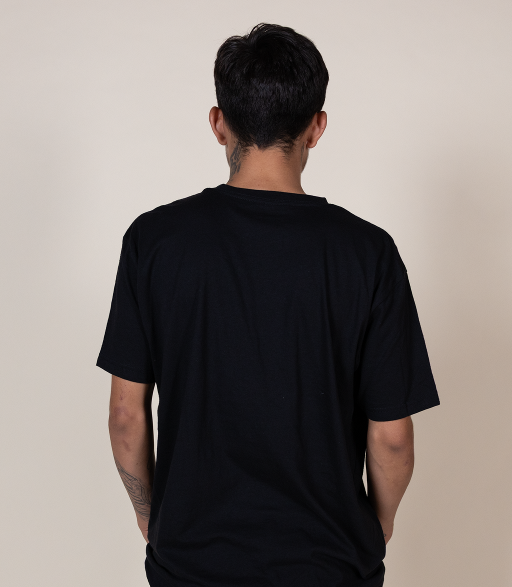 A man viewed from behind wearing a plain black short-sleeve t-shirt against a solid light beige background.